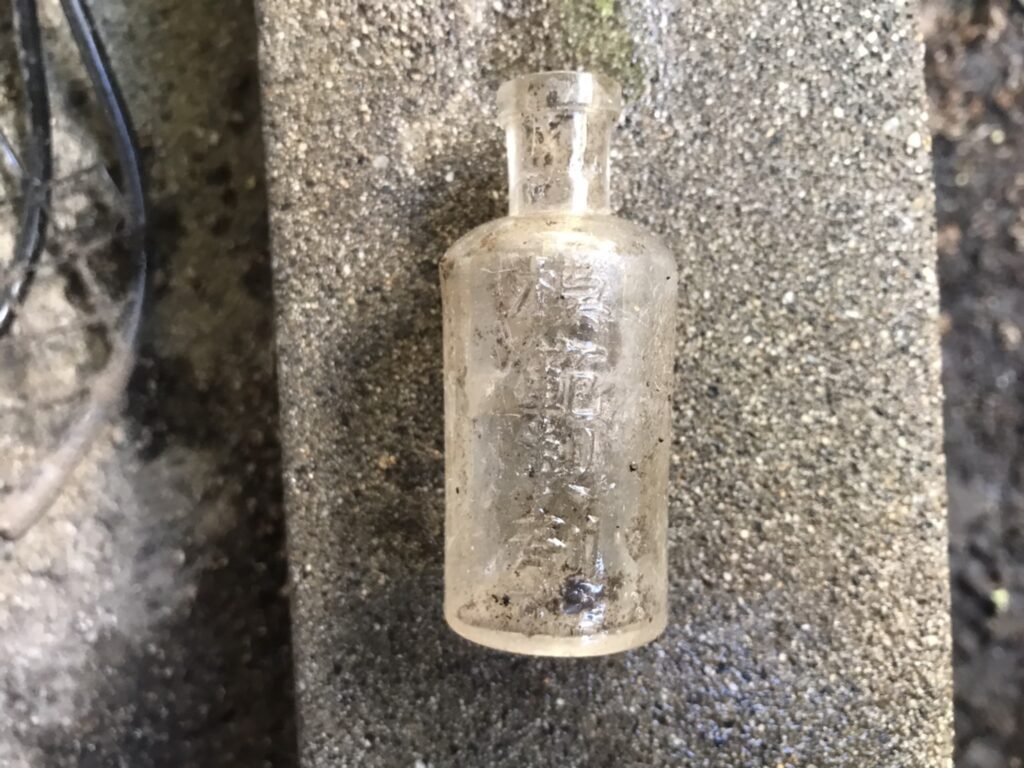 土から出てきた模範製剤の瓶の写真